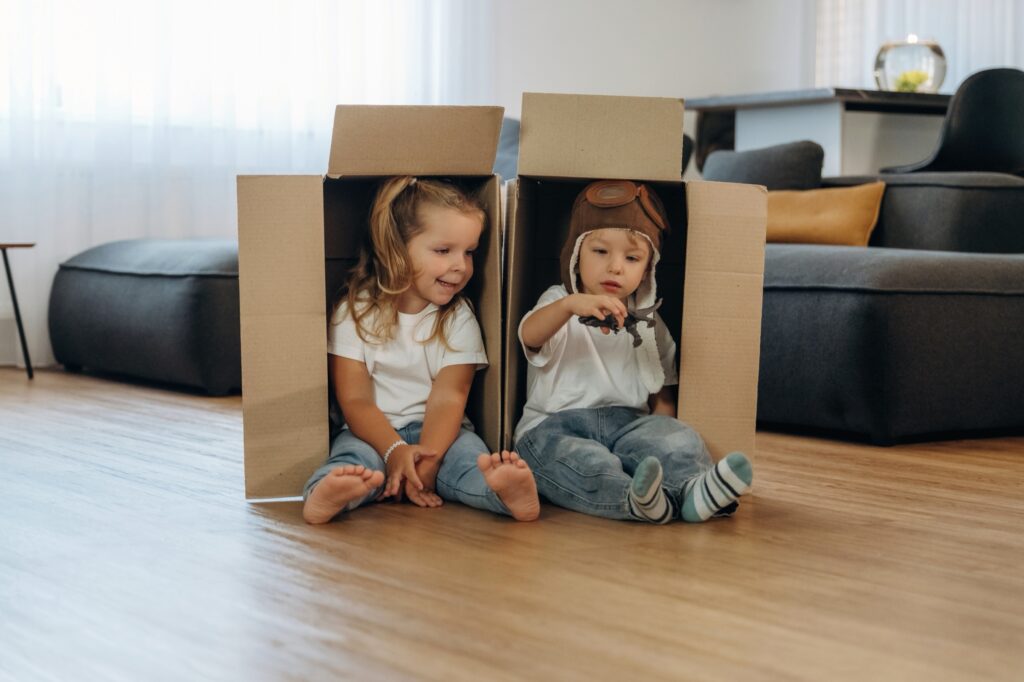 Two little kids laughing in cardboard boxes